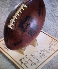 Vintage game-worn football on wooden stand